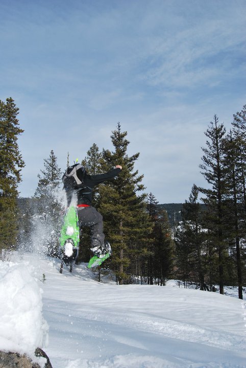 Snowshoer jumping off rock